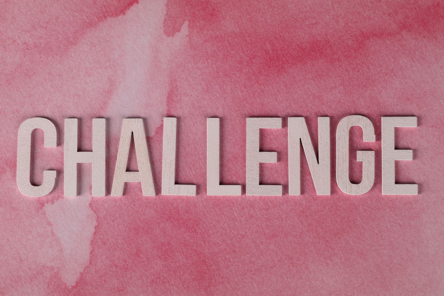 Text 'CHALLENGE' in bold on textured pink watercolor background for motivation.